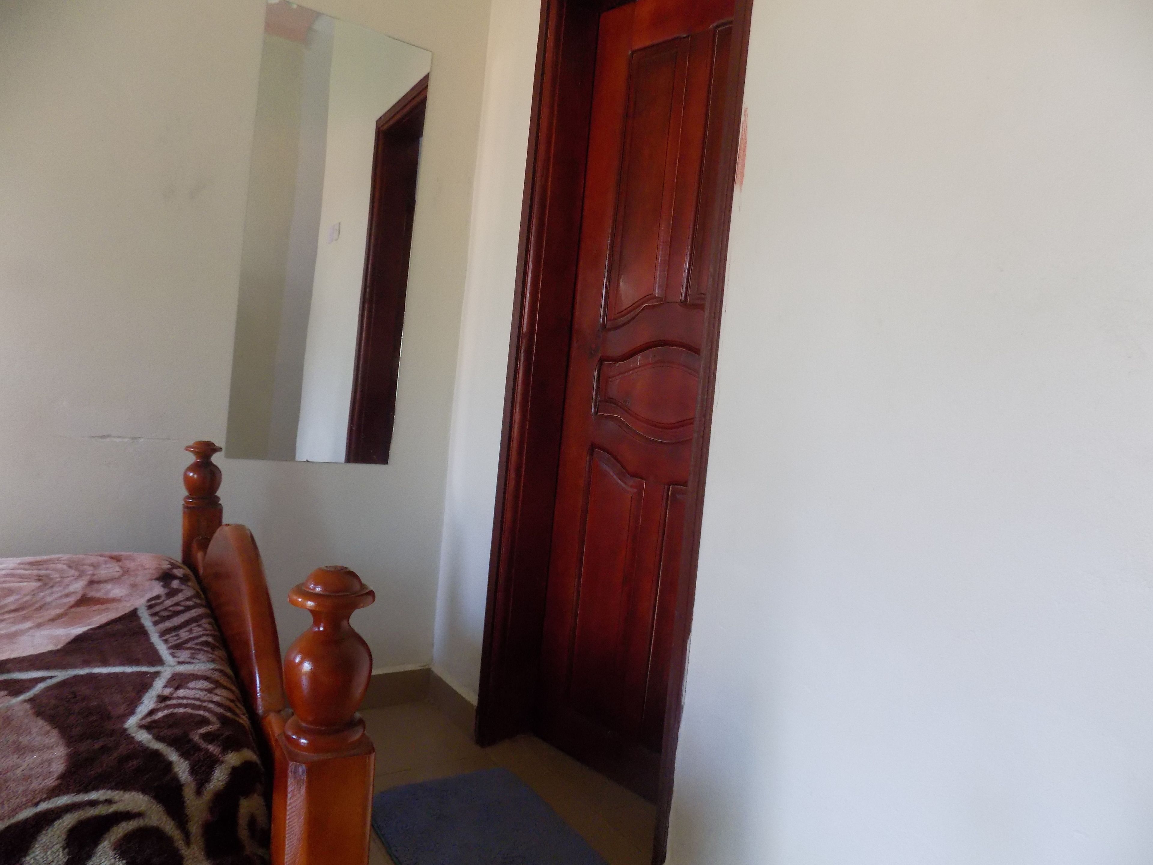A bedroom with a wooden bed, a mirror, and a wooden door.