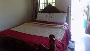 A bed with a wooden headboard, a red and white bedspread, and pillows labeled "Deluxe Inn." - Deluxe Hotel - Ishaka (Ishaka)