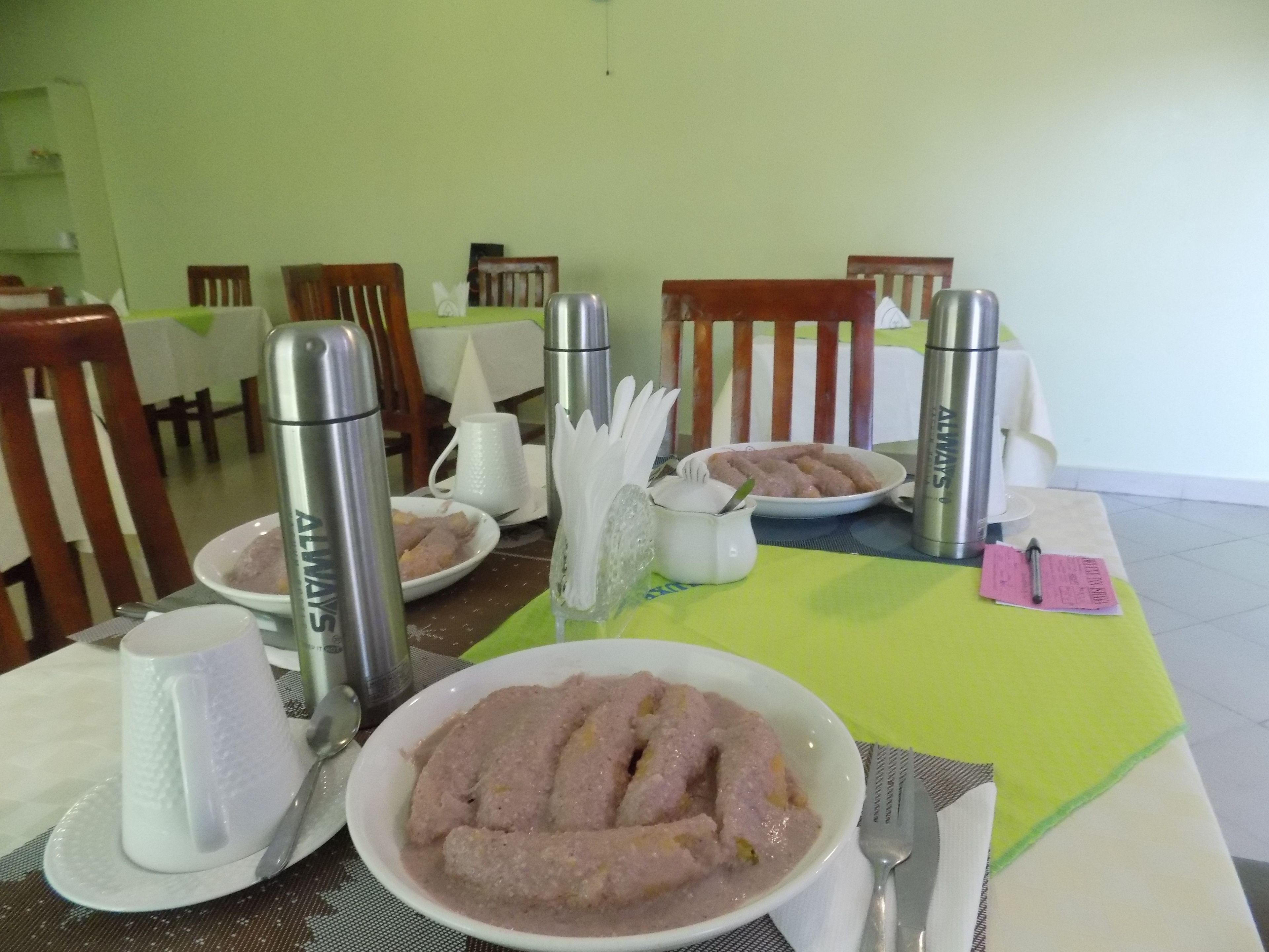 A dining table set with plates of food, cutlery, and thermos flasks.