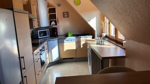 A modern kitchen with built-in appliances, a window for natural light, and a view of the outside.