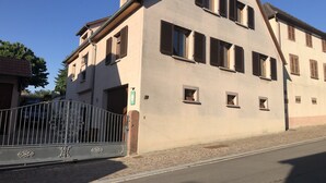 A two-story building with a sloped roof, multiple windows with shutters, and a gated entrance.
