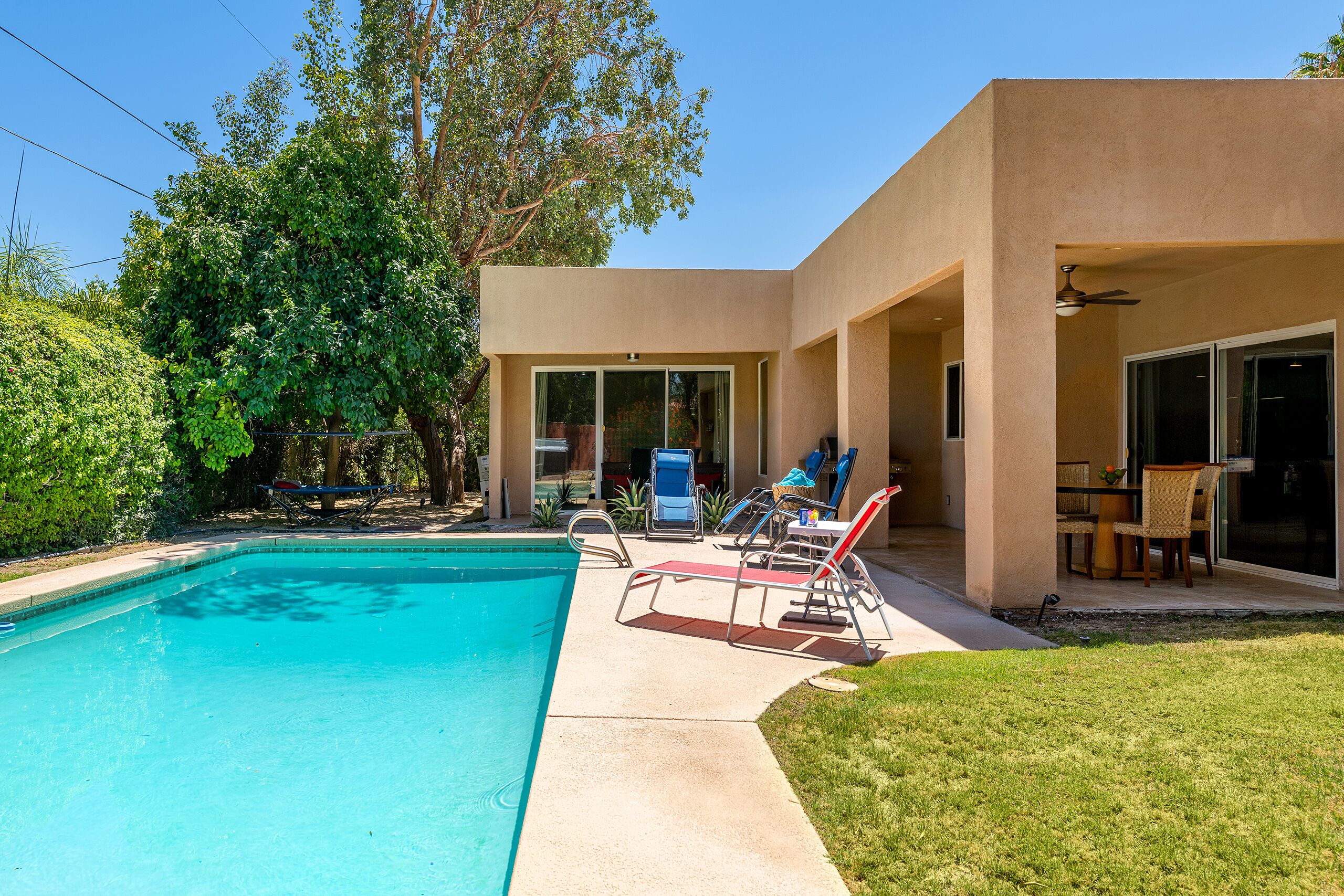 A modern house with a swimming pool, outdoor furniture, and a patio area.
