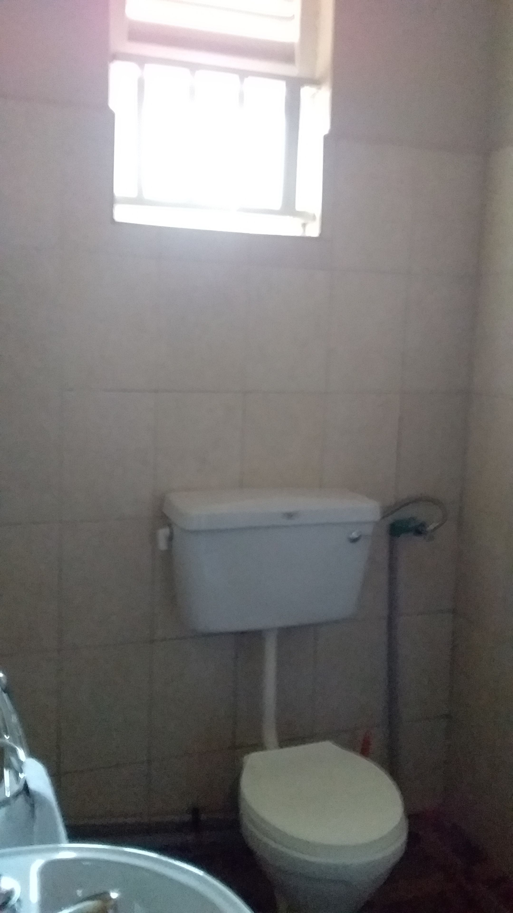 Une salle de bain avec des toilettes, un lavabo et une fenêtre.