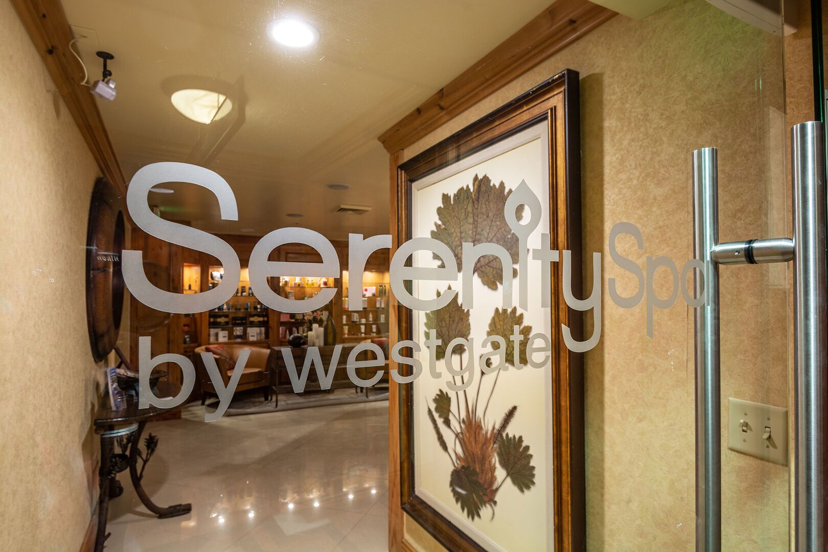 A hallway with a framed botanical print on the wall, a wooden floor, and a ceiling with recessed lighting.