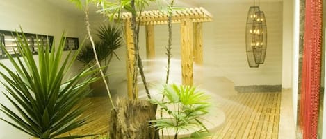 A modern interior with a wooden pergola, indoor plants, and a hanging light fixture.