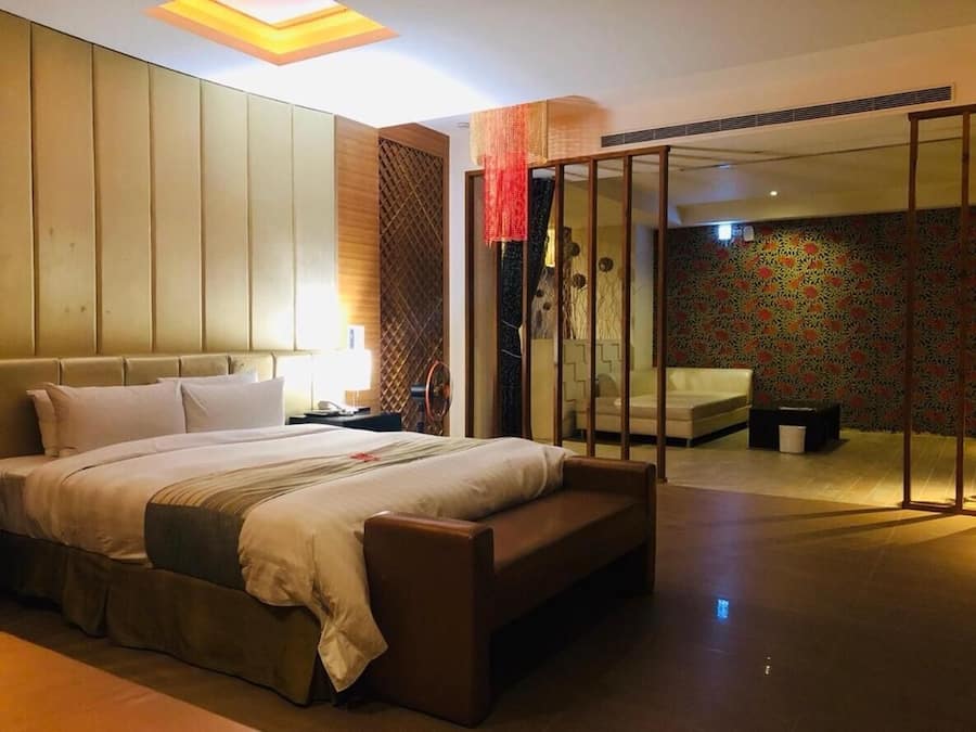 Quarto de hotel moderno com uma cama grande, uma escrivaninha e uma porta de vidro deslizante que dá para uma varanda.