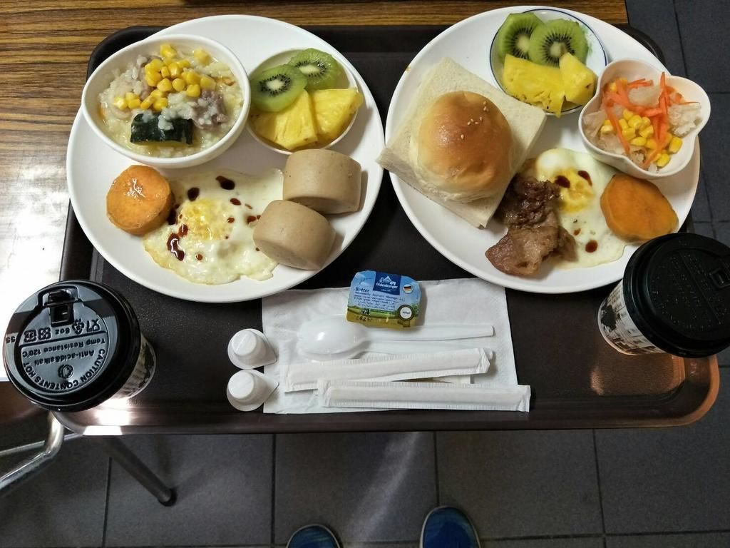 A tray with two plates of food, a bottle of water, and a pack of tissues.