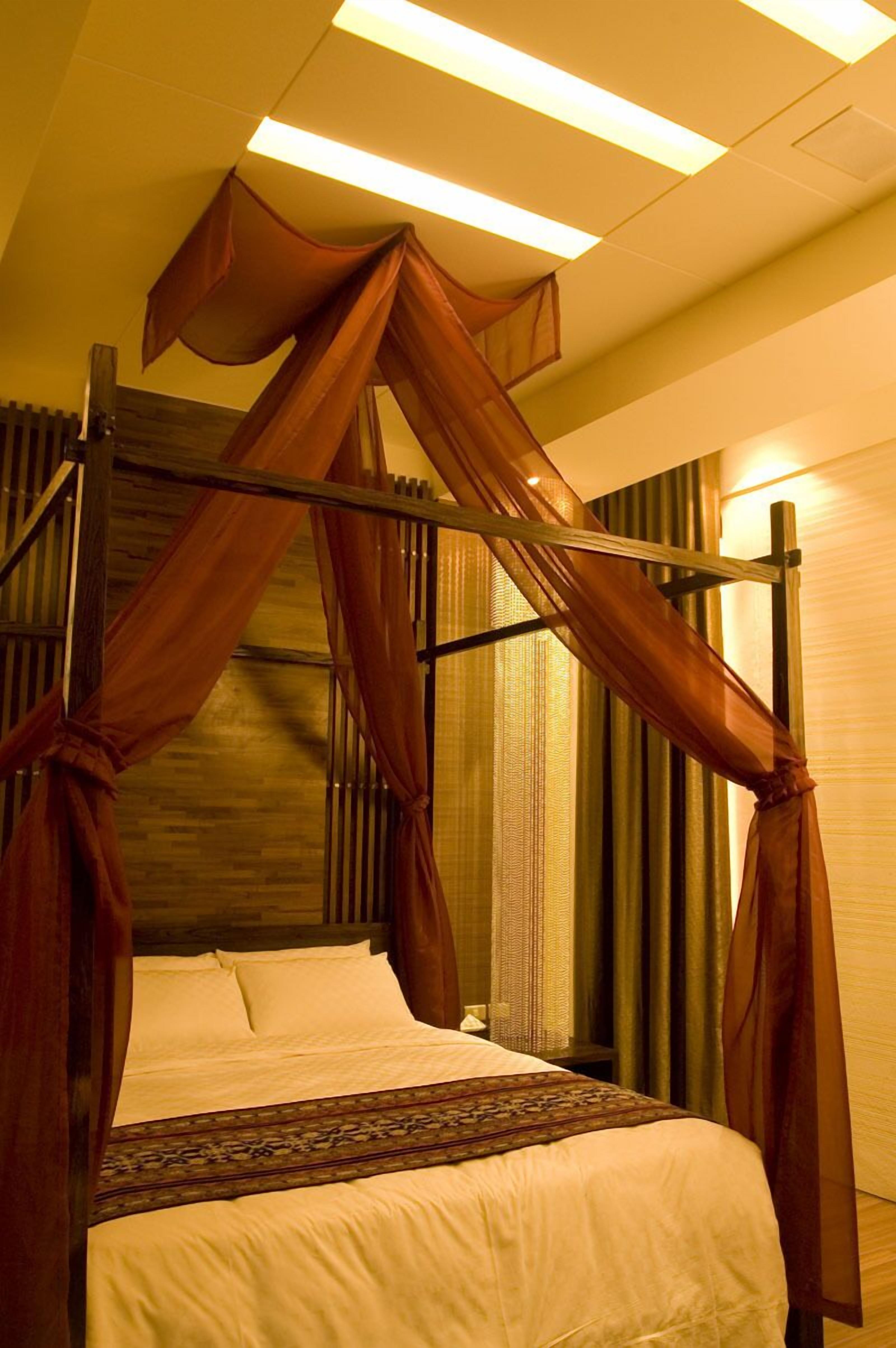 A four-poster bed with a canopy, a wooden headboard, and a patterned bedspread.