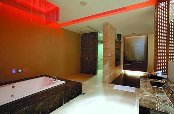 A modern bathroom with a large bathtub, a separate shower area, and a vanity with a mirror.
