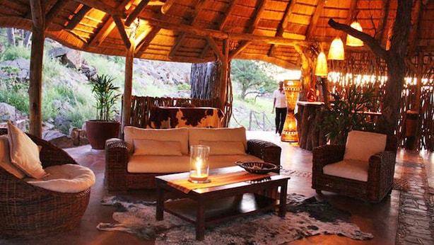 An indoor seating area with wicker furniture, a coffee table, and a thatched roof.