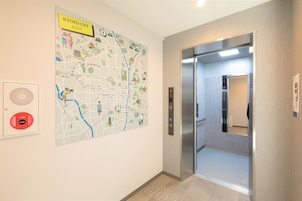 A map of Kyoto City on the wall, an elevator, and a fire alarm panel.