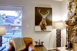 Relax in a cozy space with a leather armchair and throw blanket, overlooking a residential area.