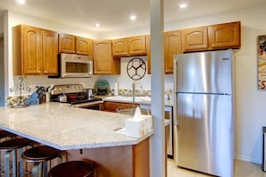 A kitchen with wooden cabinets, a stainless steel refrigerator, a microwave, and a coffee station. - Ski In & Walk Out-Patio with Slope Views-HotTub (Steamboat Springs)