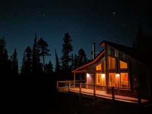 Situated in a forested area, this cabin offers a balcony with a view of the night sky.