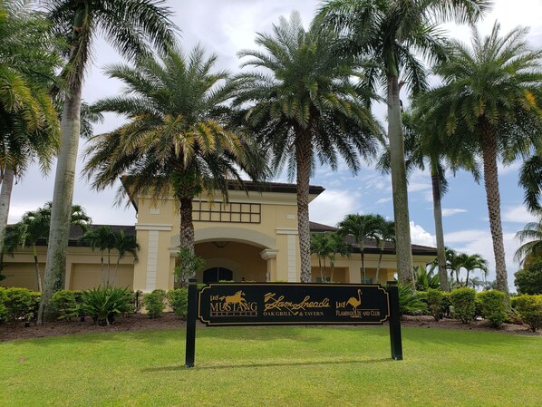 Señal de club de golf con un edificio al fondo.