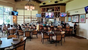 A bar area with multiple TVs, a bar counter, and seating for patrons. - Vacation in paradise at Lely Resort (Naples)