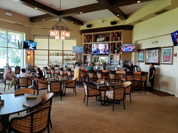 A bar area with multiple TVs, a bar counter, and seating for patrons. - Vacation in paradise at Lely Resort (Naples)