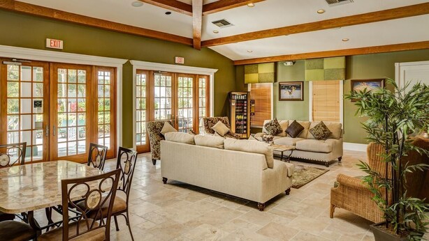 A spacious indoor area with a high ceiling, wooden beams, a large sofa, a dining table with chairs, and a bookshelf. - Vacation in paradise at Lely Resort (Naples)