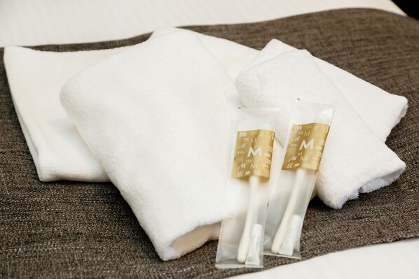 A neatly folded white towel with a gold tag on it, placed on a textured brown surface.
