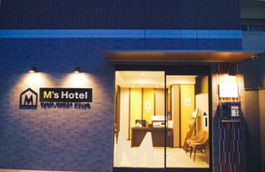 The exterior of M's Hotel with a reception desk, a large 'M' logo, and a parking sign. - M’s Hotel Kyoto Station Kizuya (Kyoto)