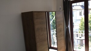 Ett hotellrum med en säng, en garderob och ett stort fönster med gardiner.