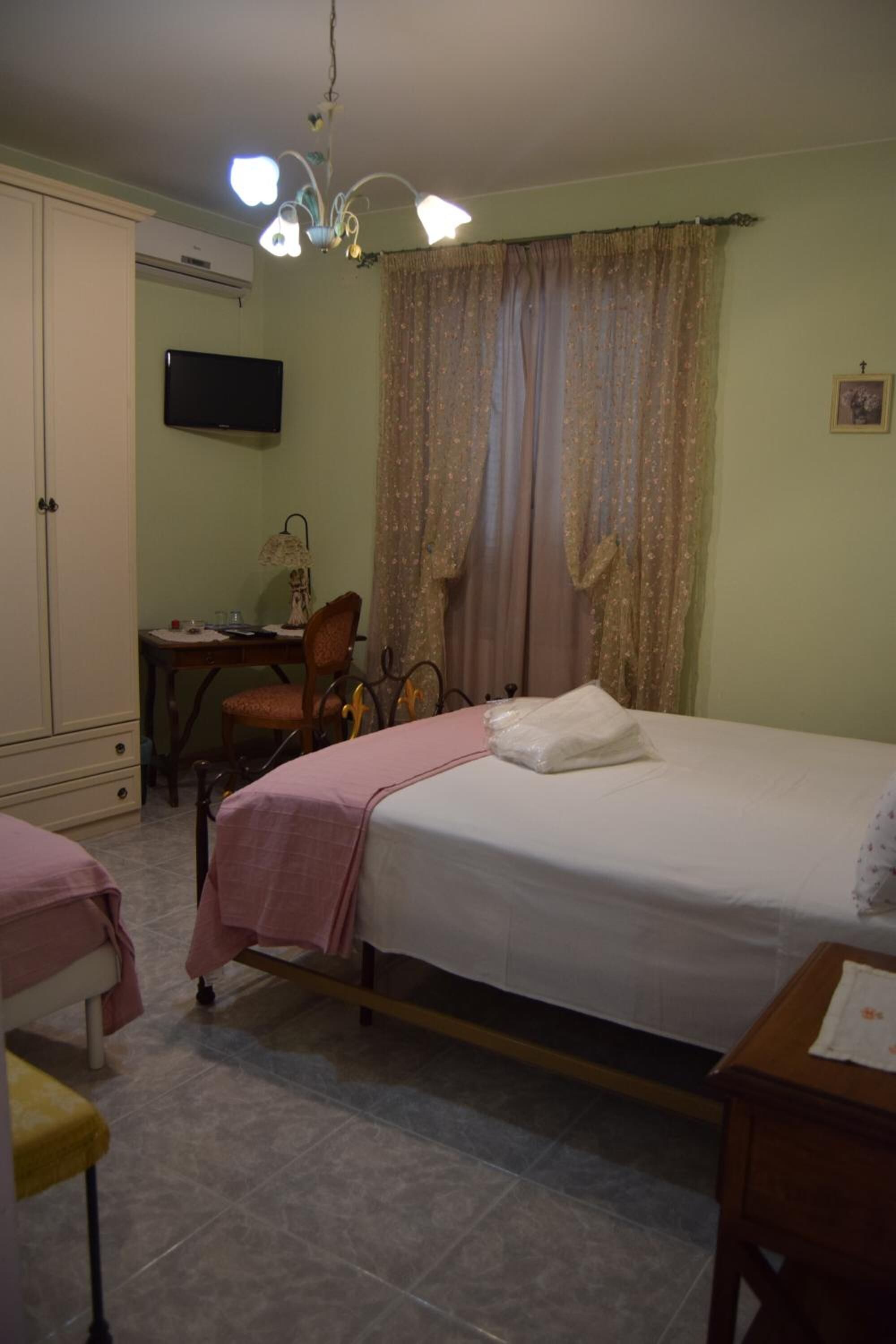 A bedroom with a bed, a desk, a chair, and a television.