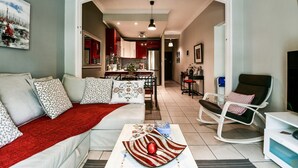 A living room with a sofa, a coffee table, a rocking chair, and a TV. - Star Acropolis apartment in Acropolis (Athens)
