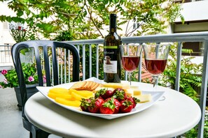 A table with a bottle of wine, glasses, a plate of fruit, and a chair. - Star Acropolis apartment in Acropolis (Athens)