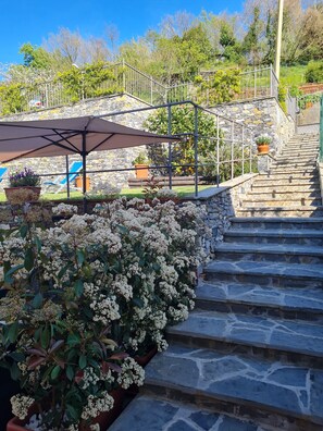 A stone staircase leading up to a covered area with outdoor seating and potted plants. - The "BARLETTI MILL" WITH HEATED POOL. (Casarza Ligure)