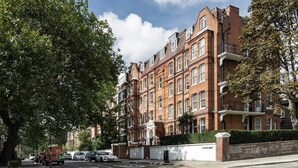 A multi-story brick building with a symmetrical facade, large windows, and a gated entrance. - Cosy 1 bedroom in Belsize Park (London)
