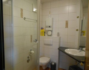 Un bagno con box doccia in vetro, un water, un lavandino e uno specchio.