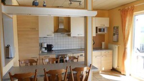 Une cuisine compacte avec un coin repas, dotée de meubles en bois, d’un four à micro-ondes et d’une machine à café.
