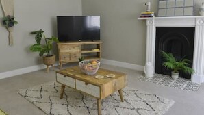 Ein Wohnzimmer mit Fernseher auf einem Holzboden, Kamin und Couchtisch mit Korb.