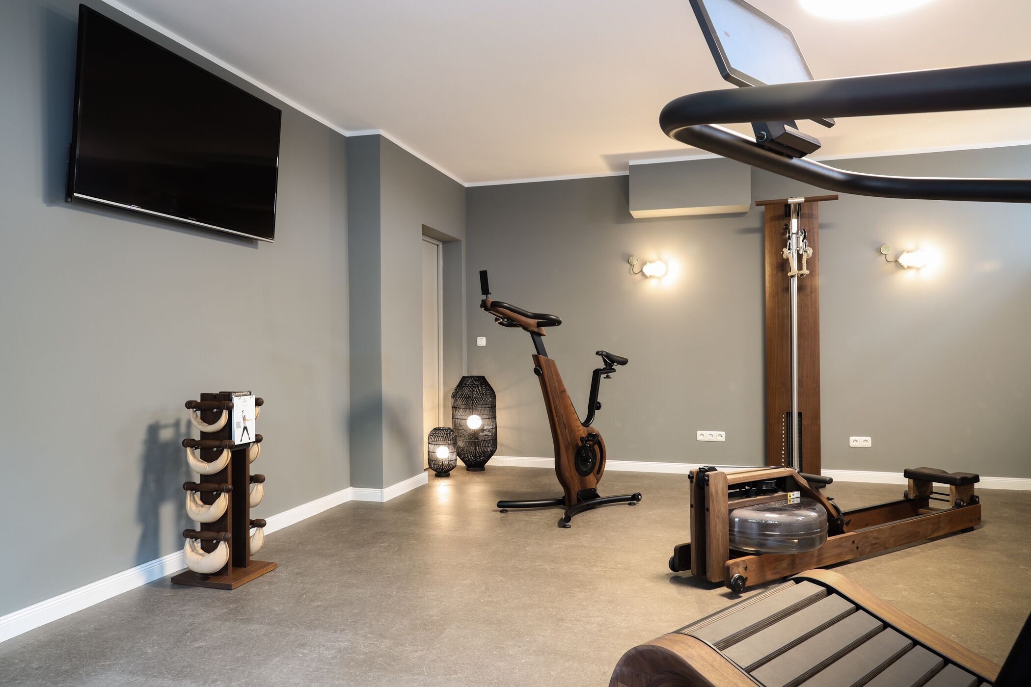 Un gimnasio en casa con una bicicleta estática, una elíptica y una barra de dominadas.