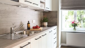 Una cocina moderna con un lavamanos de acero inoxidable, encimera de madera y armarios blancos.