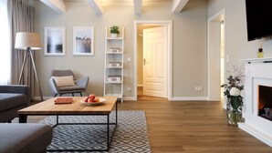 Una sala de estar moderna con sofá, mesa de centro y chimenea. Hay una estantería y un televisor montado en la pared.
