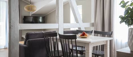 Un espace repas moderne avec une table blanche, des chaises noires et un luminaire suspendu noir.