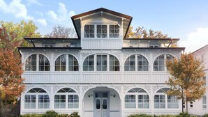 Un edificio de dos plantas con fachada simétrica, amplias ventanas de arco y una entrada central con puerta.