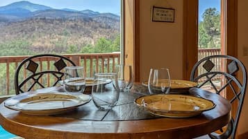 Una mesa de comedor con platos y vasos, con vistas a una montaña pintoresca.