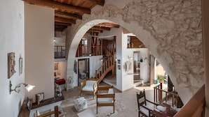 A rustic interior with a stone archway, wooden furniture, and a staircase leading to an upper level. - Kritiko Arhontiko (Apokoronas)
