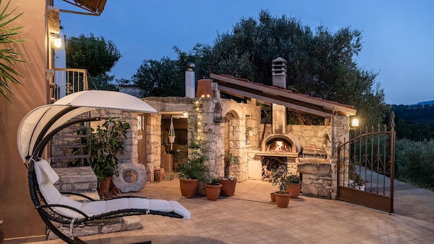 A stone building with a fireplace, outdoor seating, and potted plants. - Kritiko Arhontiko (Apokoronas)