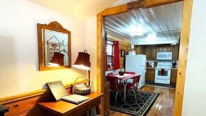A wooden dining table with chairs, a small desk with a lamp, and a mirror on the wall. - River Cabin (Ruidoso)