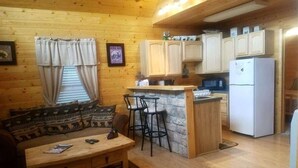 Ein gemütliches Blockhaus-Interieur mit einer Holzeinrichtungs-Essbereich, einer Küche mit einer Steininsele und einem eingebauten Kühlschrank.