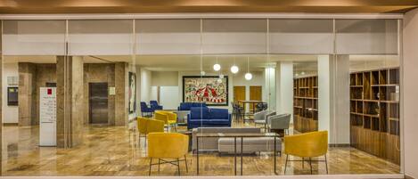 A modern lobby with a glass wall, seating area, and a reception desk.