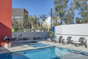 Un área de piscina en la azotea con sillones, una pequeña mesa y una planta en maceta.
