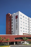 Un hotel de varios pisos con una fachada destacada de rojo y blanco, numerosas ventanas y cielo despejado.