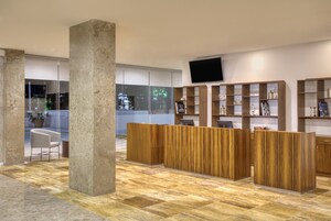 Un área de recepción con un mostrador de madera, un pilar grande y un televisor de pantalla plana en la pared.