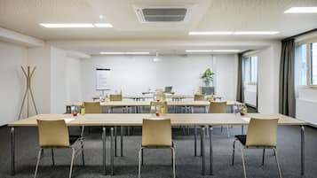 Een vergaderzaal met een lange tafel, stoelen, een beamer en een whiteboard.
