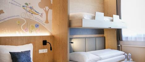 Habitación de hotel con literas, una mesita con botellas de agua y un mural temático de naturaleza en la pared.