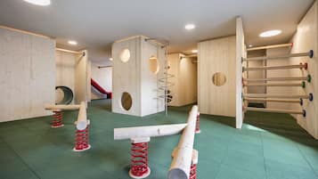 Zona de juegos con estructuras de madera, un tobogán y una pared de escalar.